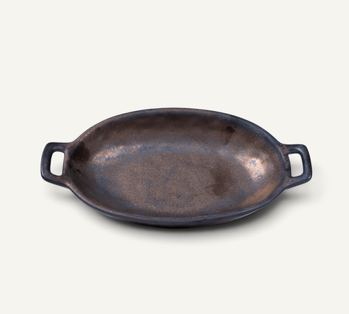 An oval bronze color Japanese ceramic serving bowl with side handles, photographed on a clean, solid off-white background.