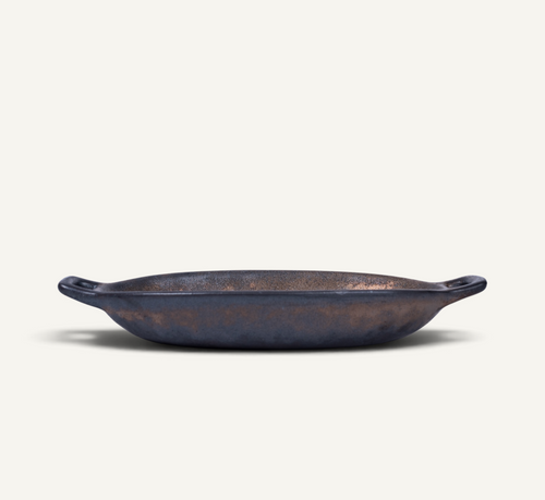 An oval bronze color Japanese ceramic serving bowl with side handles, photographed on a clean, solid off-white background.