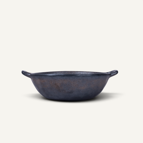 A Japanese style ceramic bowl with two side handles, photographed from a top-down perspective on a light cream background.
