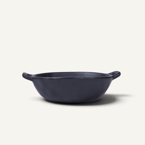 A Japanese style ceramic bowl with two side handles, photographed from a top-down perspective on a light cream background.