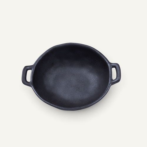 A Japanese style ceramic bowl with two side handles, photographed from a top-down perspective on a light cream background.