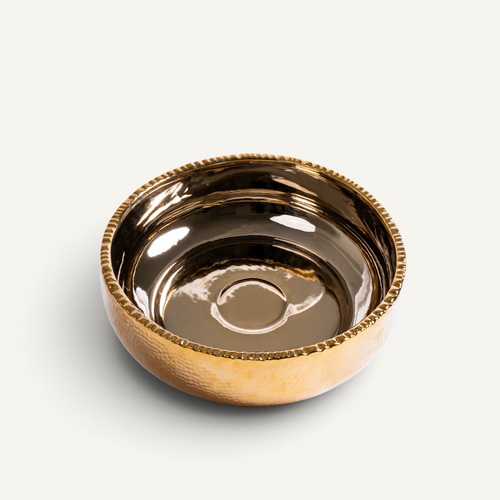 A small round ceramic bowl with a hammered gold finish on the exterior and a smooth reflective bronze interior, shown on a light gray background.