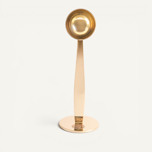 Three stainless steel espresso scoops in silver, copper, and gold colors with integrated tampers, displayed on a white background.