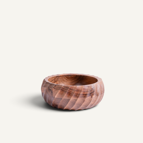 A small acacia wooden bowl with a carved spiral pattern, shown on a light off-white background.