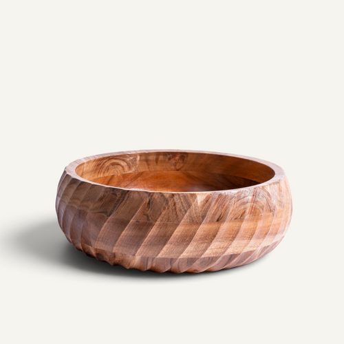 A round acacia bowl with a matching lid, both featuring a carved spiral pattern, displayed on a light beige background.