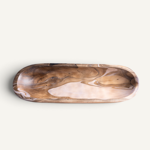 An elongated oval wooden tray with a polished finish, featuring a natural swirling wood grain pattern in shades of brown and beige, set against a plain off-white background.
