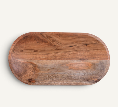 An oval wooden serving board with rounded corners, showcasing natural wood grain and knots, photographed from directly above on a light off-white background.