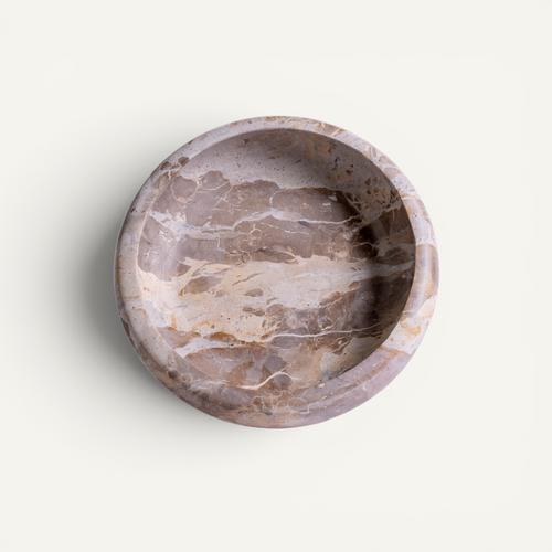 A round stone bowl with a natural marble pattern in shades of taupe, beige, and brown, photographed from a top-down perspective on a light off-white background.