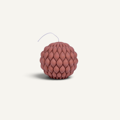 A spherical, textured candle with a dusty rose or terracotta color and a thin wick, shown on a clean, off-white background.
