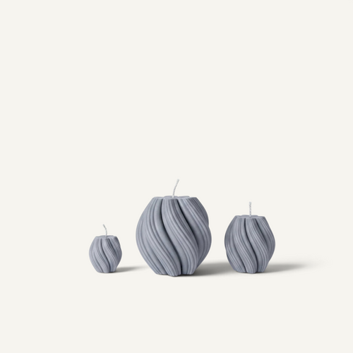 Three ribbed, vase-shaped candles in a matching light gray color, arranged by size against a clean off-white background.