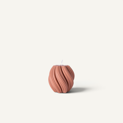A ribbed, textured candle in a dusty rose or terracotta color, photographed against a solid off-white background.