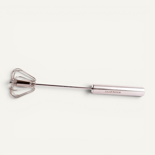 A stainless steel hand whisk shown on a clean off-white background.