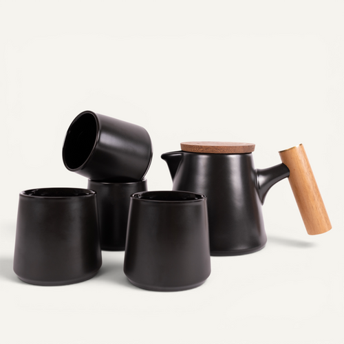 A set of green ceramic tea cups and a teapot with a solid walnut handle and a stainless steel infuser basket.