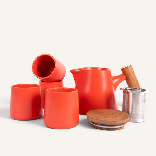 A set of red ceramic tea cups and a teapot with a solid walnut handle and a stainless steel infuser basket.