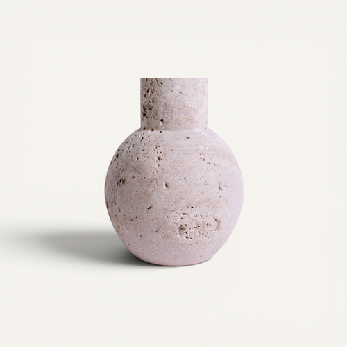 A round stone vase with a short cylindrical neck, featuring a textured, porous surface in a pale pinkish-beige color, set against a solid off-white background.